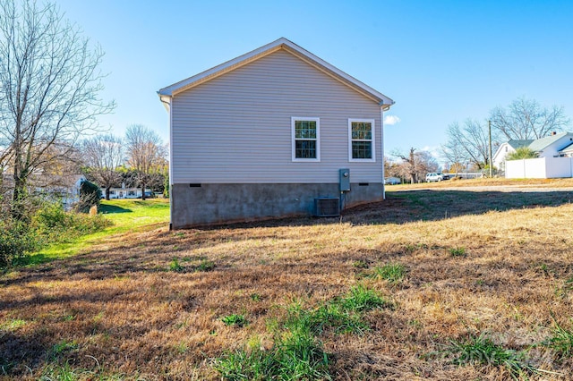 view of side of property with a yard and central AC