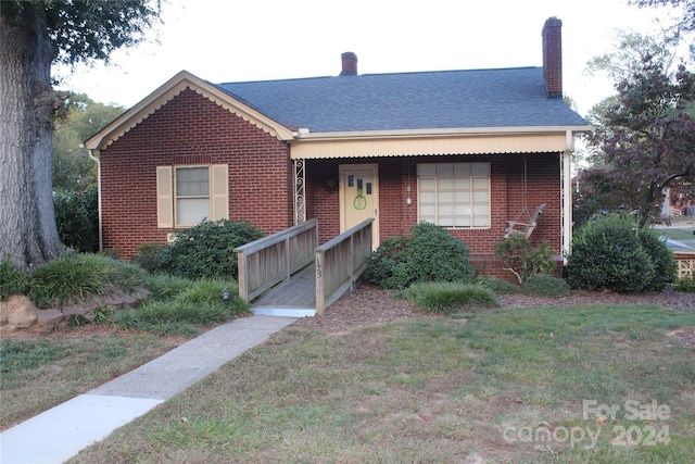 ranch-style home featuring covered porch and a front lawn