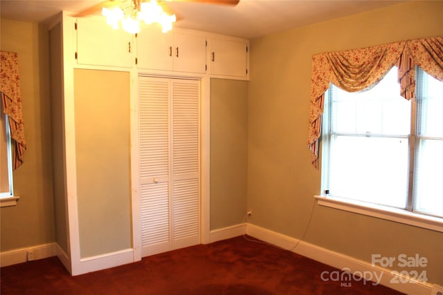 unfurnished bedroom with dark colored carpet, a closet, and ceiling fan