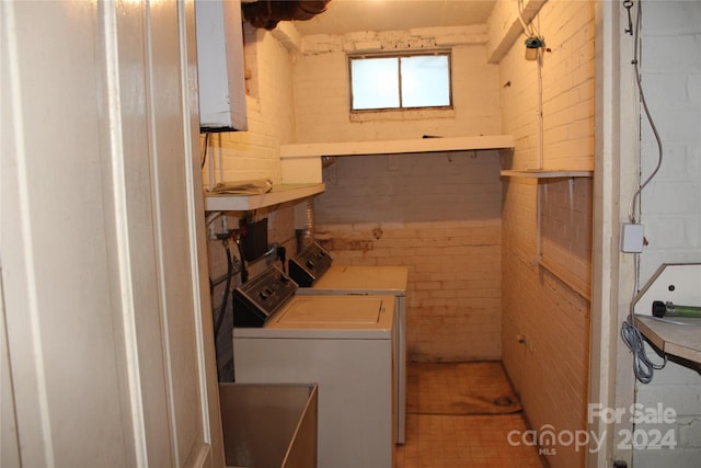 washroom featuring washer and dryer and brick wall