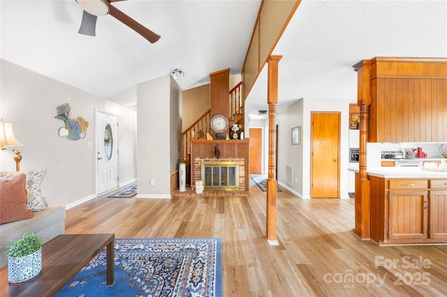 living room with a fireplace, light hardwood / wood-style floors, and ceiling fan