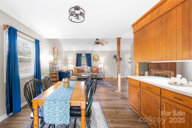 dining area with hardwood / wood-style flooring, ceiling fan, a fireplace, and decorative columns