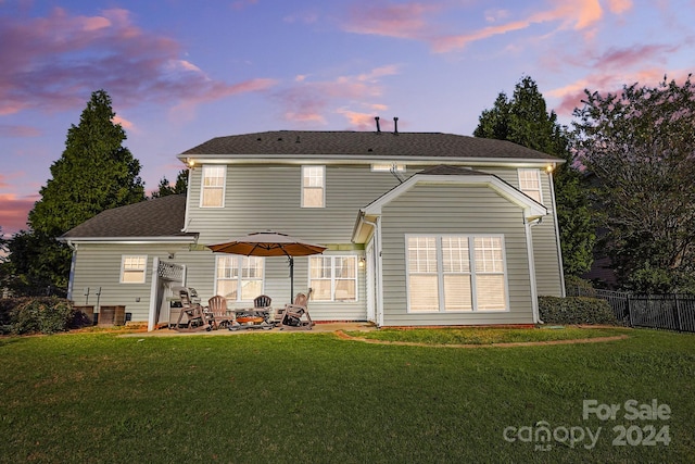 back house at dusk with a lawn