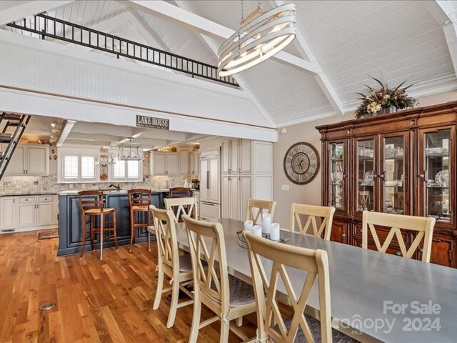 dining room with beam ceiling, high vaulted ceiling, and light wood-type flooring