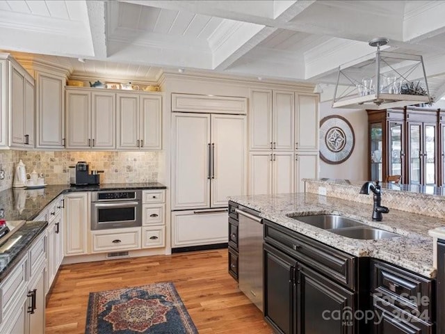 kitchen featuring oven, paneled built in refrigerator, light hardwood / wood-style floors, decorative light fixtures, and beam ceiling