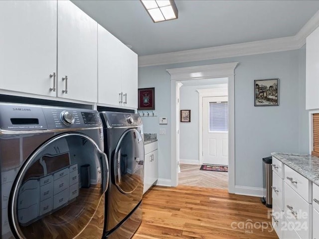 laundry room with cabinets, light hardwood / wood-style flooring, washing machine and dryer, and crown molding