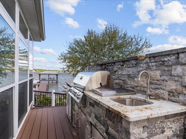 wooden terrace featuring sink, area for grilling, a water view, and a boat dock