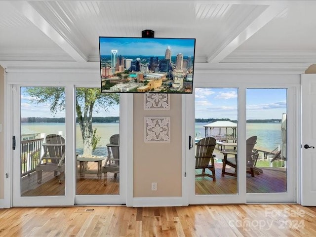 doorway featuring beam ceiling, crown molding, wood-type flooring, and a wealth of natural light