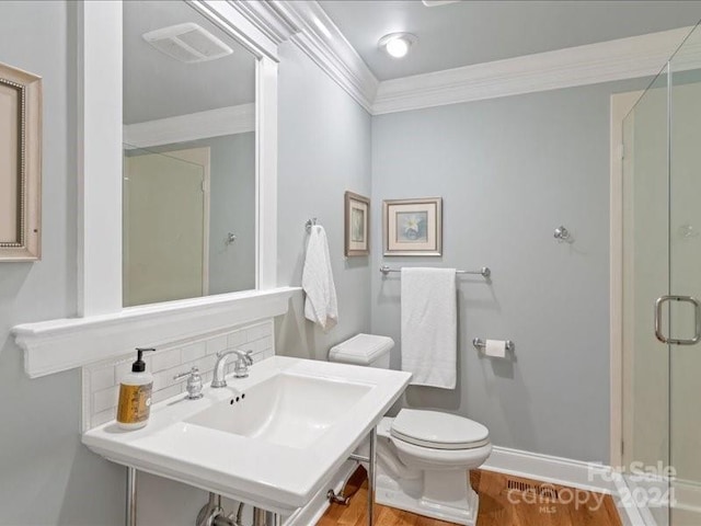 bathroom with decorative backsplash, hardwood / wood-style flooring, toilet, ornamental molding, and an enclosed shower