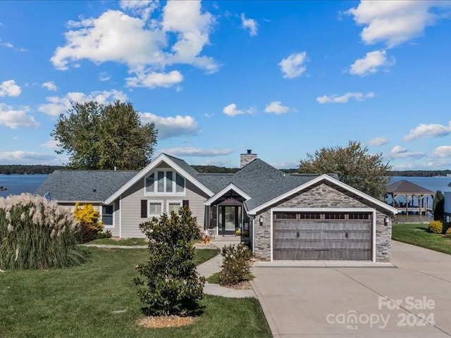 view of front facade featuring a garage, a front lawn, and a water view