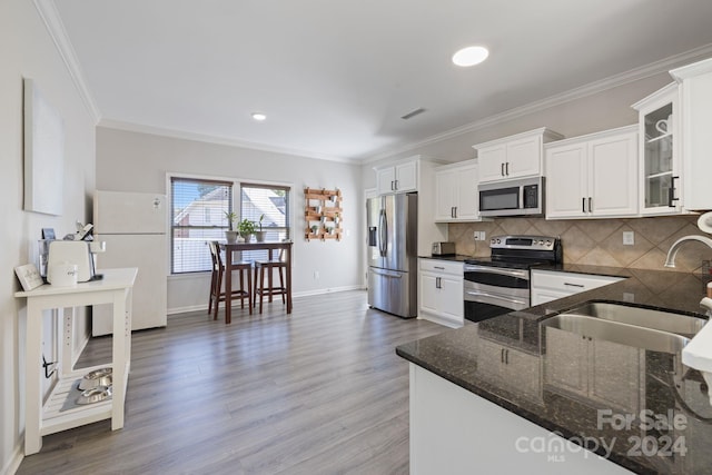 kitchen with white cabinetry, sink, stainless steel appliances, and hardwood / wood-style flooring