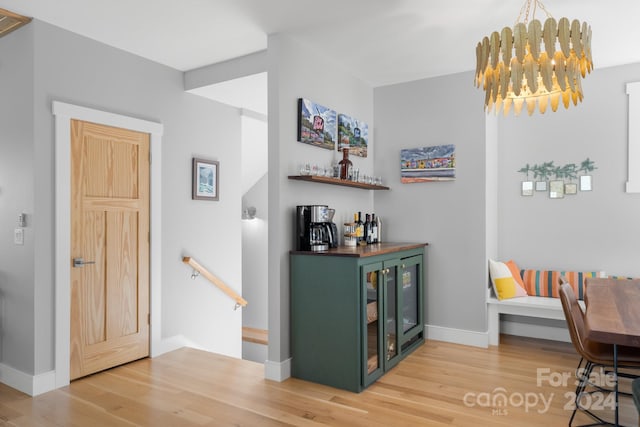 bar with green cabinets, a chandelier, and hardwood / wood-style floors