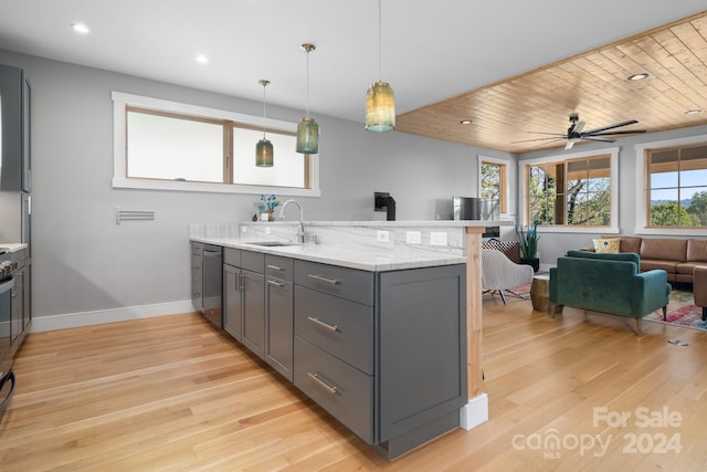 kitchen with gray cabinetry, kitchen peninsula, light stone countertops, and light wood-type flooring