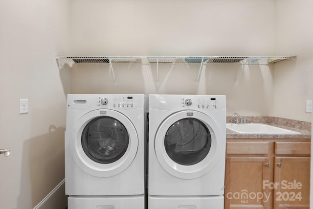 washroom featuring cabinets, washing machine and dryer, and sink