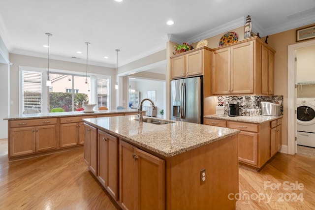 kitchen featuring stainless steel refrigerator with ice dispenser, a center island with sink, hanging light fixtures, and sink