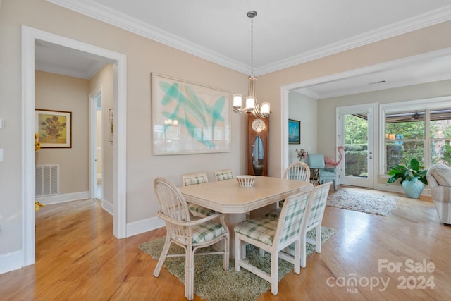 dining area with light wood-type flooring, an inviting chandelier, and crown molding