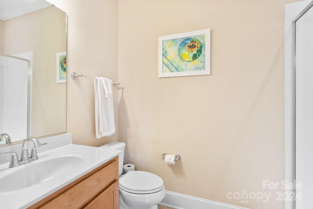 bathroom with an enclosed shower, vanity, and toilet