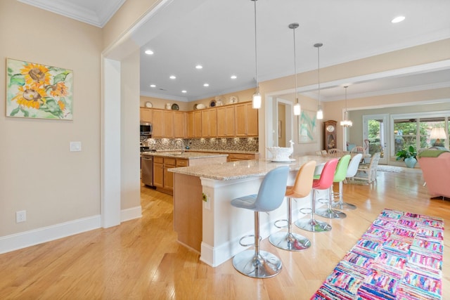 kitchen featuring tasteful backsplash, light stone counters, ornamental molding, stainless steel appliances, and light hardwood / wood-style flooring