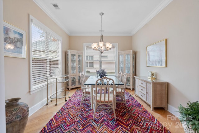 dining space featuring light hardwood / wood-style flooring, ornamental molding, and a notable chandelier