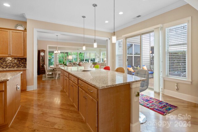 kitchen featuring backsplash, plenty of natural light, hanging light fixtures, and light wood-type flooring