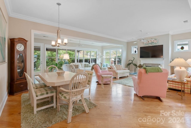 dining room featuring light wood-type flooring, a wealth of natural light, and crown molding