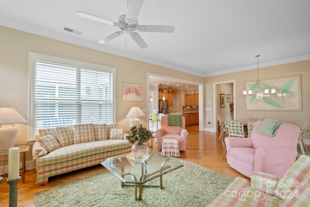 living room with crown molding, ceiling fan with notable chandelier, and light wood-type flooring