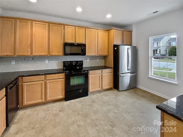 kitchen with dark stone countertops, black appliances, and decorative backsplash