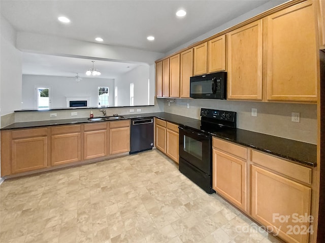 kitchen featuring kitchen peninsula, dark stone countertops, sink, black appliances, and a notable chandelier