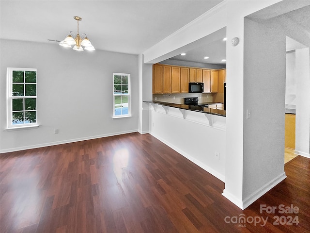 kitchen with kitchen peninsula, black appliances, a notable chandelier, decorative light fixtures, and dark hardwood / wood-style flooring