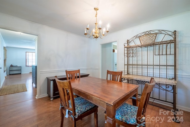 dining area featuring a notable chandelier, ornamental molding, and hardwood / wood-style flooring