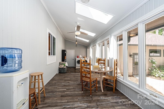 dining space featuring washer / clothes dryer, ceiling fan, vaulted ceiling with skylight, dark wood-type flooring, and ornamental molding