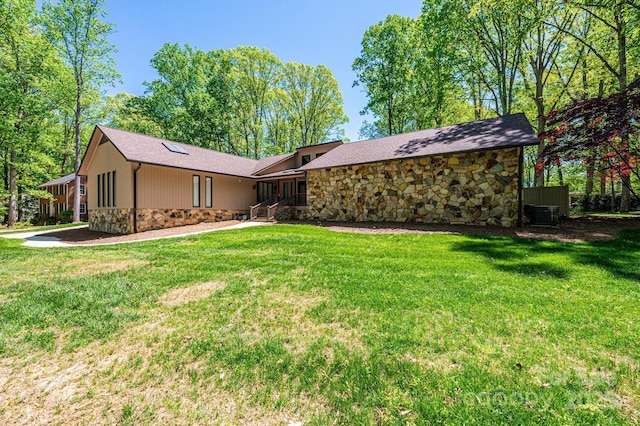 rear view of property with central air condition unit and a lawn