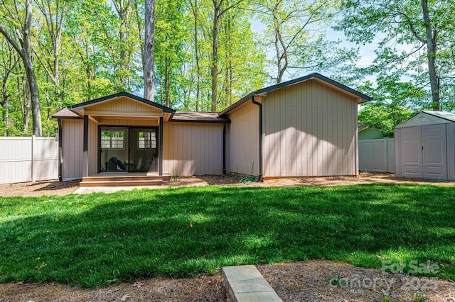 rear view of house with a shed and a lawn