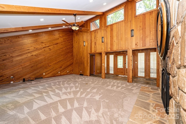 unfurnished living room featuring beam ceiling, wood walls, high vaulted ceiling, light carpet, and a fireplace