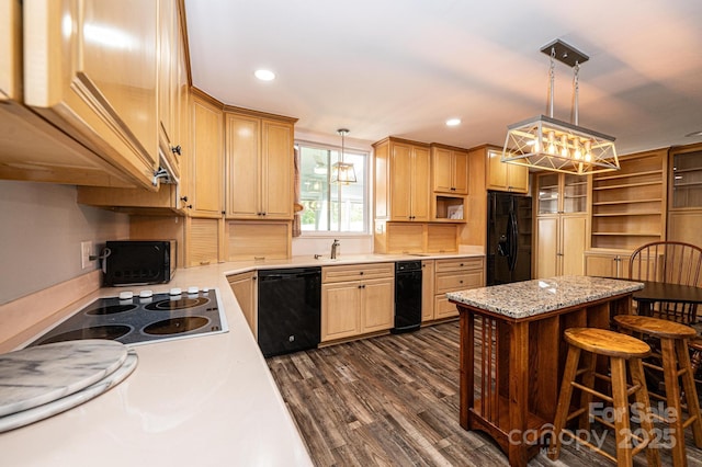 kitchen featuring decorative light fixtures, dark wood-type flooring, black appliances, and a kitchen breakfast bar