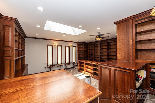 unfurnished office featuring crown molding, built in shelves, ceiling fan, and a skylight