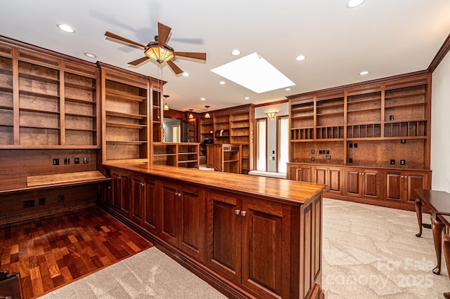 kitchen featuring wood counters, a skylight, light hardwood / wood-style flooring, ornamental molding, and kitchen peninsula