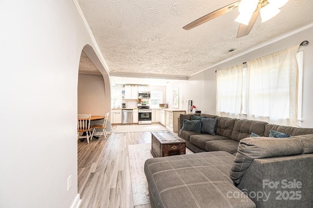 living room with ceiling fan, light hardwood / wood-style floors, a textured ceiling, and a wealth of natural light