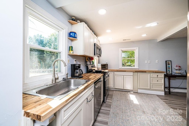 kitchen with wooden counters, appliances with stainless steel finishes, dark hardwood / wood-style flooring, sink, and white cabinetry