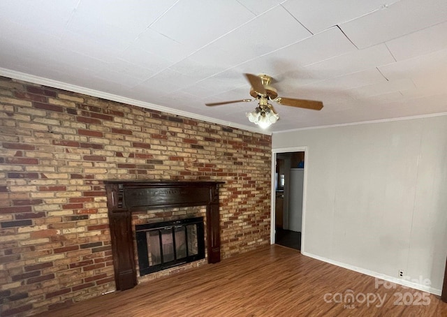 unfurnished living room featuring ceiling fan, ornamental molding, brick wall, dark hardwood / wood-style flooring, and a brick fireplace