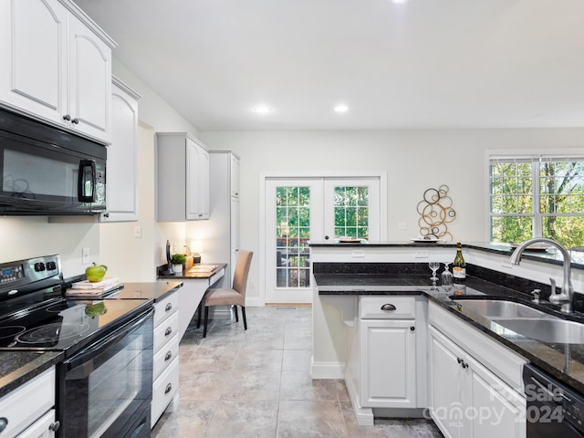 kitchen featuring black appliances, dark stone counters, a wealth of natural light, sink, and white cabinets