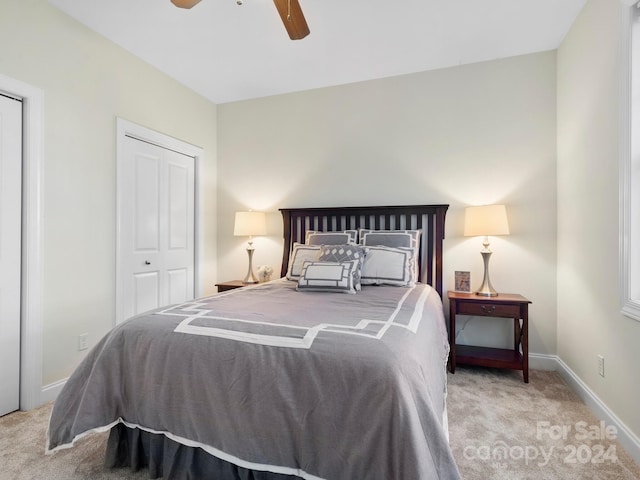 bedroom with ceiling fan, light carpet, and a closet