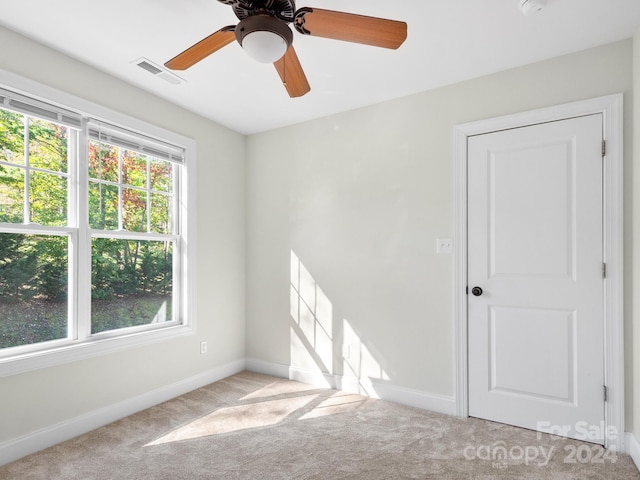 unfurnished room with ceiling fan, light colored carpet, and a healthy amount of sunlight