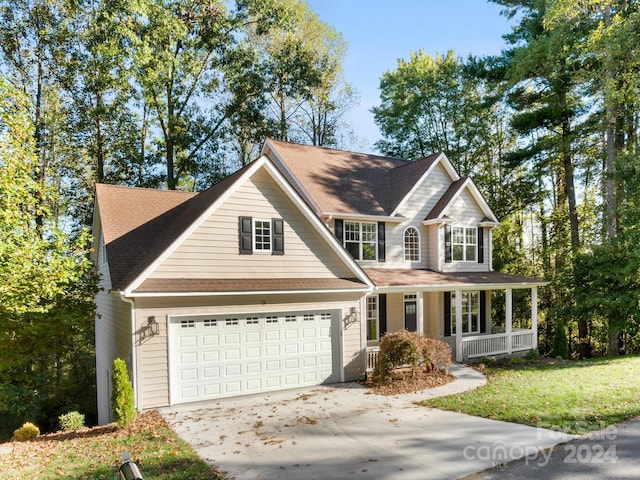 view of front of house with a garage, a front yard, and a porch