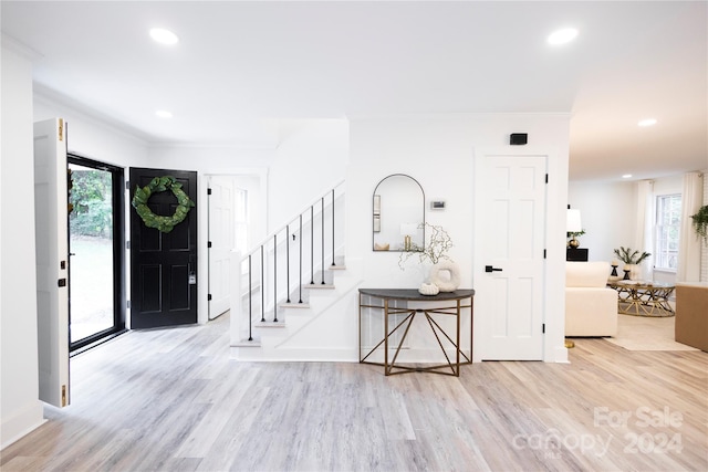 entrance foyer featuring a healthy amount of sunlight, ornamental molding, and light hardwood / wood-style flooring