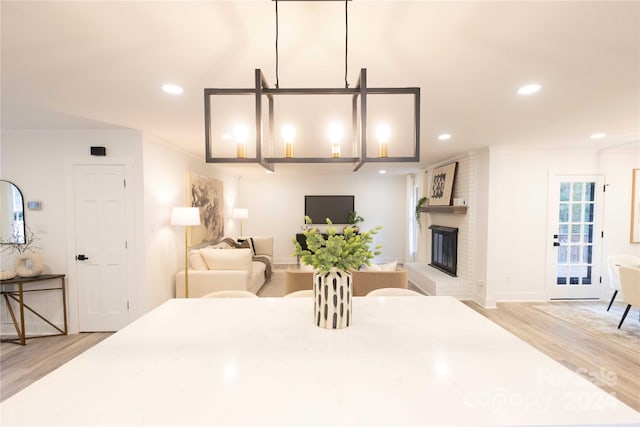 dining area with crown molding, light wood-type flooring, and a brick fireplace