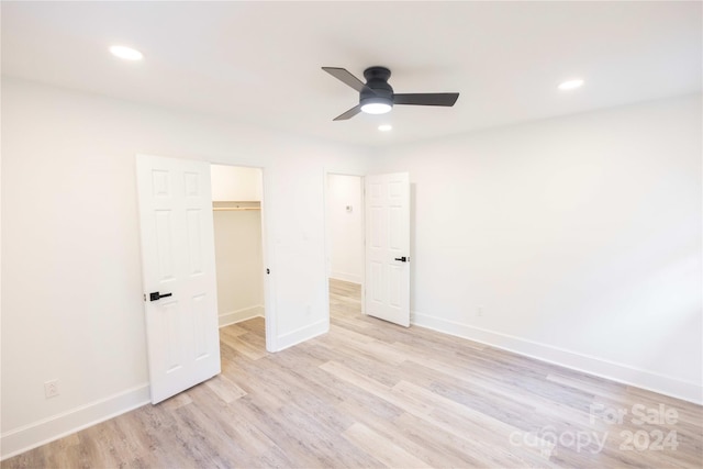 unfurnished bedroom with a closet, a walk in closet, light wood-type flooring, and ceiling fan