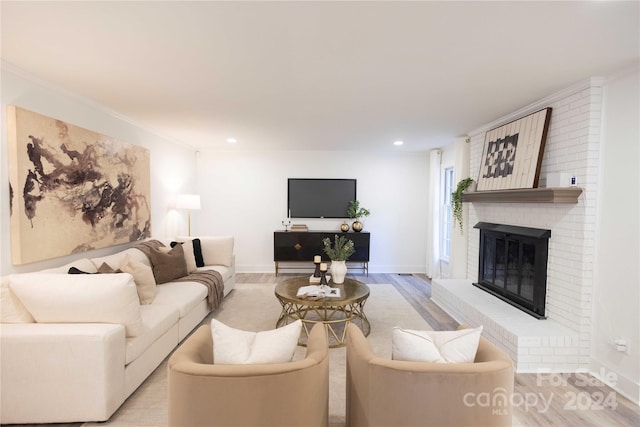 living room with light hardwood / wood-style flooring, ornamental molding, and a fireplace