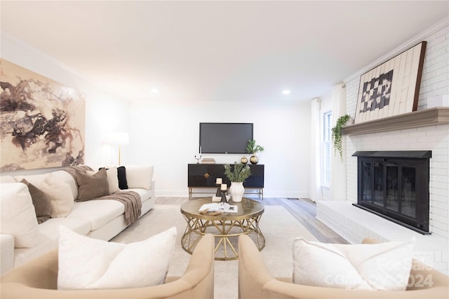 living room with ornamental molding, a brick fireplace, and light wood-type flooring