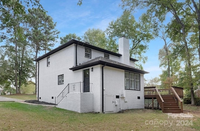 rear view of property featuring a deck and a lawn